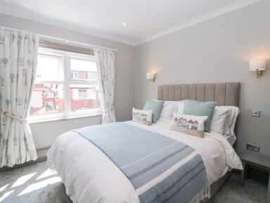 A bedroom with a bed with blue and white bedding and curtains with hot air balloon pattern at 41 Chatsworth Gardens in Scarborough