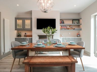 A dining area with a wooden table set with plates bowls and glasses surrounded by grey chairs and a wooden bench at 41 Chatsworth Gardens in Scarborough