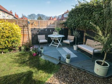 A small garden with a wooden deck area furnished with a table and chairs surrounded by plants and a wooden fence at 41 Chatsworth Gardens in Scarborough