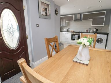A kitchen with wooden dining table and chairs a vase with flowers on the table and modern cabinets at 4 Tyne View in Wark