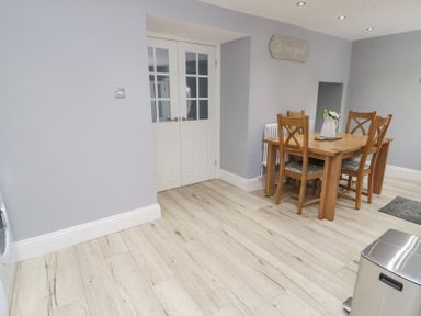 A dining area with wooden table and chairs a white double door a wall sign and wood flooring at 4 Tyne View in Wark