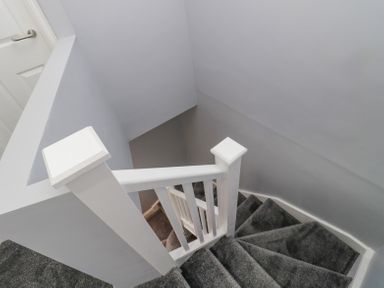 A stairway with grey carpet and white wooden handrails at 4 Tyne View in Wark