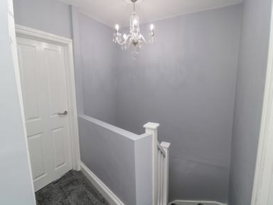 A staircase landing with a closed white door and a chandelier at 4 Tyne View in Wark
