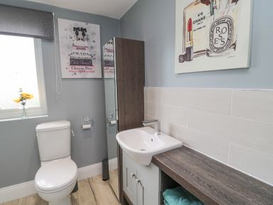 A bathroom with a toilet, a sink, a cabinet, and wall art at 4 Tyne View in Wark