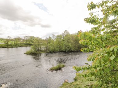 A river surrounded by trees and greenery at 4 Tyne View in Wark