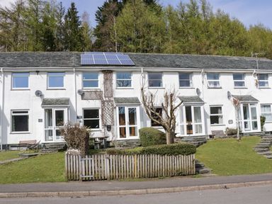 A row of white terraced houses with solar panels on the roof and a small fenced garden in front at Fellside View in Chapel Stile