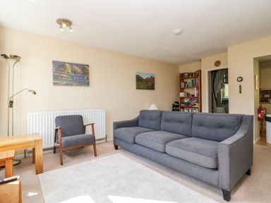 A living room with a grey sofa and armchair a bookshelf and two landscape paintings at Fellside View in Chapel Stile