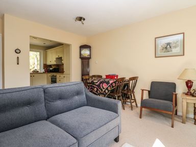 A living room with a gray sofa a wooden dining table with chairs a framed picture and a tall clock at Fellside View in Chapel Stile