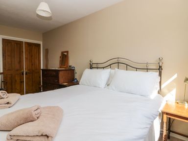 A bedroom with a metal bed frame white bedding a wooden dresser bedside tables and folded towels at Fellside View in Chapel Stile