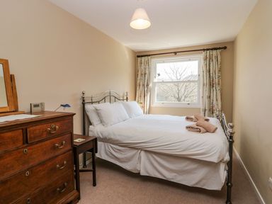 A bedroom with a double bed and white bedding with folded towels on the bed and a wooden chest of drawers next to the bed at Fellside View in Chapel Stile