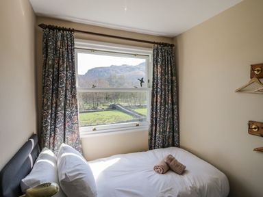 A bedroom with a bed beside a window showing a mountain view at Fellside View in Chapel Stile