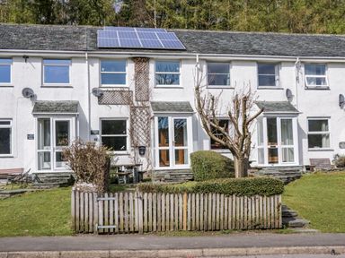 A row of white terraced houses with solar panels on the roof and a small fenced garden in front at Fellside View in Chapel Stile