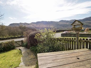 A garden with wooden fence and birdhouse overlooking hills and road at Fellside View in Chapel Stile