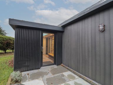 An exterior entrance with a glass door on a black corrugated wall and a small grassy area at Skylark in Bishop Wilton