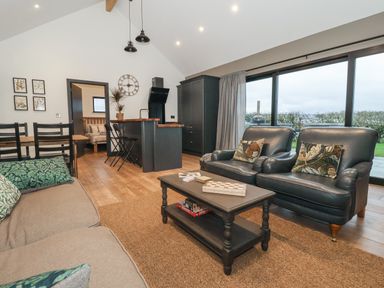 A living room with sofa chairs coffee table and kitchen area with stools at Skylark in Bishop Wilton