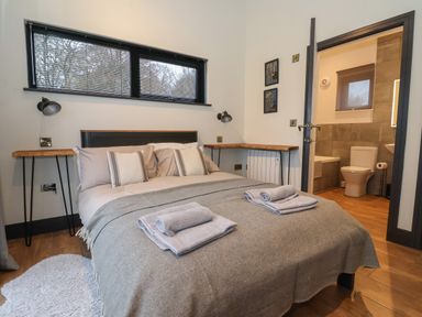 A bedroom with a double bed with pillows and folded towels and an en suite bathroom at Skylark in Bishop Wilton