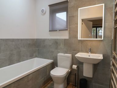 A bathroom with a bathtub toilet sink mirror and window at Skylark in Bishop Wilton