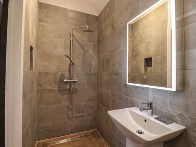 A bathroom with a walk-in shower and a sink with a lit rectangular mirror at Skylark in Bishop Wilton