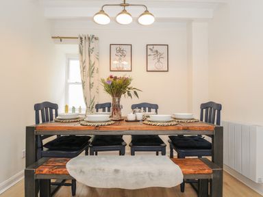 A dining room with a wooden table set for four with four chairs and a bench at Carvannel Cottages North Cliffs near Portreath