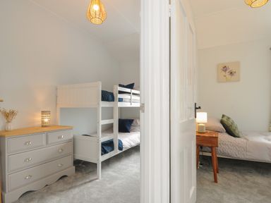 A room with a bunk bed and dresser next to an adjoining room with a single bed and bedside table at Carvannel Cottages North Cliffs near Portreath