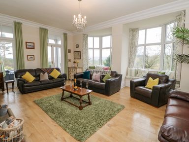 A living room with leather sofas a wooden coffee table with glasses and a bottle on a green rug at Heatherbrae in Middleton-In-Teesdale