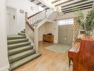 An entrance hall with a staircase green carpet and wooden furniture at Heatherbrae in Middleton-In-Teesdale