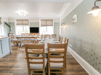 A dining room with wooden tables and chairs set with plates and glasses at Heatherbrae in Middleton-In-Teesdale
