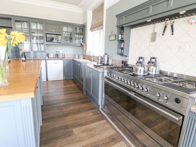A kitchen with blue cabinets a large stainless steel oven a wooden countertop and yellow flowers at Heatherbrae in Middleton-In-Teesdale