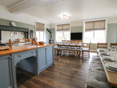 A kitchen and dining area with wooden tables and chairs set with plates and glasses at Heatherbrae in Middleton-In-Teesdale