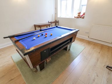 A game room with a blue pool table balls and cues a small table and two teddy bears on a window ledge at Heatherbrae in Middleton-In-Teesdale