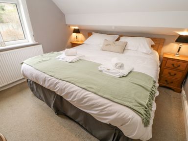 A bedroom with a double bed two wooden bedside tables with lamps and a window at Heatherbrae in Middleton-In-Teesdale