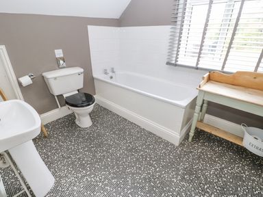 A bathroom with a toilet a bathtub a sink and a wooden side table at Heatherbrae in Middleton-In-Teesdale