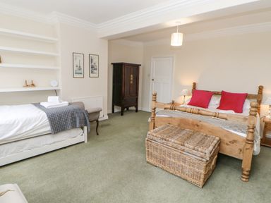 A bedroom with two beds a wicker basket a dark cabinet and framed pictures on the wall at Heatherbrae in Middleton-In-Teesdale