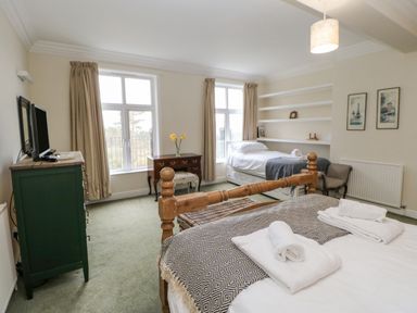 A bedroom with two beds a green dresser a wooden desk and a chair at Heatherbrae in Middleton-In-Teesdale