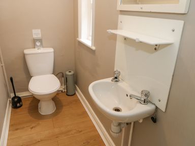 A small bathroom with a toilet a sink a window and wooden floor at Heatherbrae in Middleton-In-Teesdale