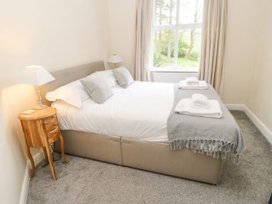 A bedroom with a double bed two bedside tables with lamps a window with curtains and folded towels on the bed at Heatherbrae in Middleton-In-Teesdale