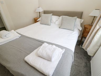 A bedroom with a bed two pillows bedside tables with lamps and folded towels at Heatherbrae in Middleton-In-Teesdale