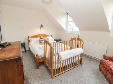 A bedroom with a wooden double bed with pillows and a wooden crib at Heatherbrae in Middleton-In-Teesdale