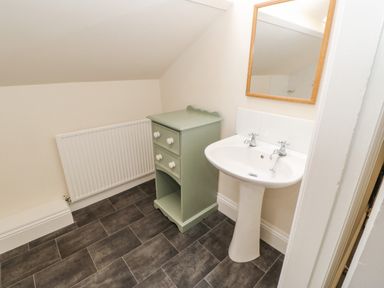 A bathroom with a white pedestal sink a wooden framed mirror a green cabinet and a white radiator at Heatherbrae in Middleton-In-Teesdale