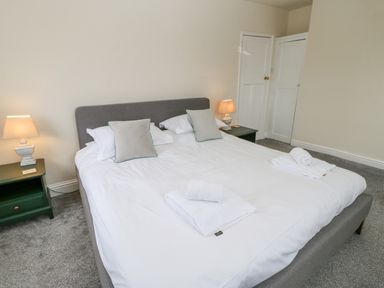 A bedroom with a large double bed two bedside tables with lamps and towels on the bed at Heatherbrae in Middleton-In-Teesdale