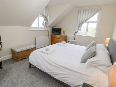A bedroom with a double bed two windows a wooden chest and dresser with a television at Heatherbrae in Middleton-In-Teesdale