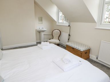 A bedroom with a bed with towels a chair sink a wooden bench under windows at Heatherbrae in Middleton-In-Teesdale