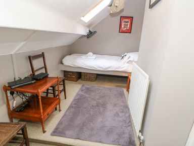 A small bedroom with a single bed a wooden table and chair and a purple rug on the floor at Heatherbrae in Middleton-In-Teesdale