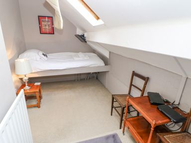 A small attic bedroom with a single bed a bedside table lamp two wooden chairs and a wooden trolley at Heatherbrae in Middleton-In-Teesdale