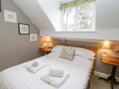 A bedroom with a double bed towels on the bed two bedside tables with lamps and framed pictures on the wall at Heatherbrae in Middleton-In-Teesdale