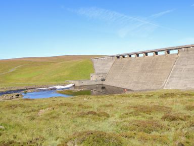 An outdoor landscape with a concrete dam and water flowing in a grassy area at Heatherbrae in Middleton-In-Teesdale