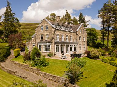 A large stone house with multiple windows and a manicured garden at Heatherbrae in Middleton-In-Teesdale