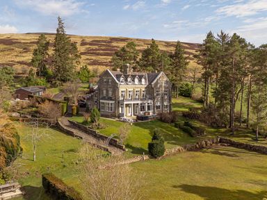 A large stone house with multiple chimneys surrounded by grass and trees Heatherbrae Middleton-In-Teesdale