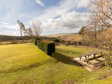 A grassy garden with trimmed hedges picnic table and distant hills at Heatherbrae in Middleton-In-Teesdale