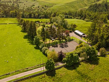A rural property with a house surrounded by trees a tennis court and farmland at Heatherbrae in Middleton-In-Teesdale